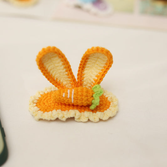 Handmade orange crochet bunny hairclip with two ears and tiny carrot, flat lay view