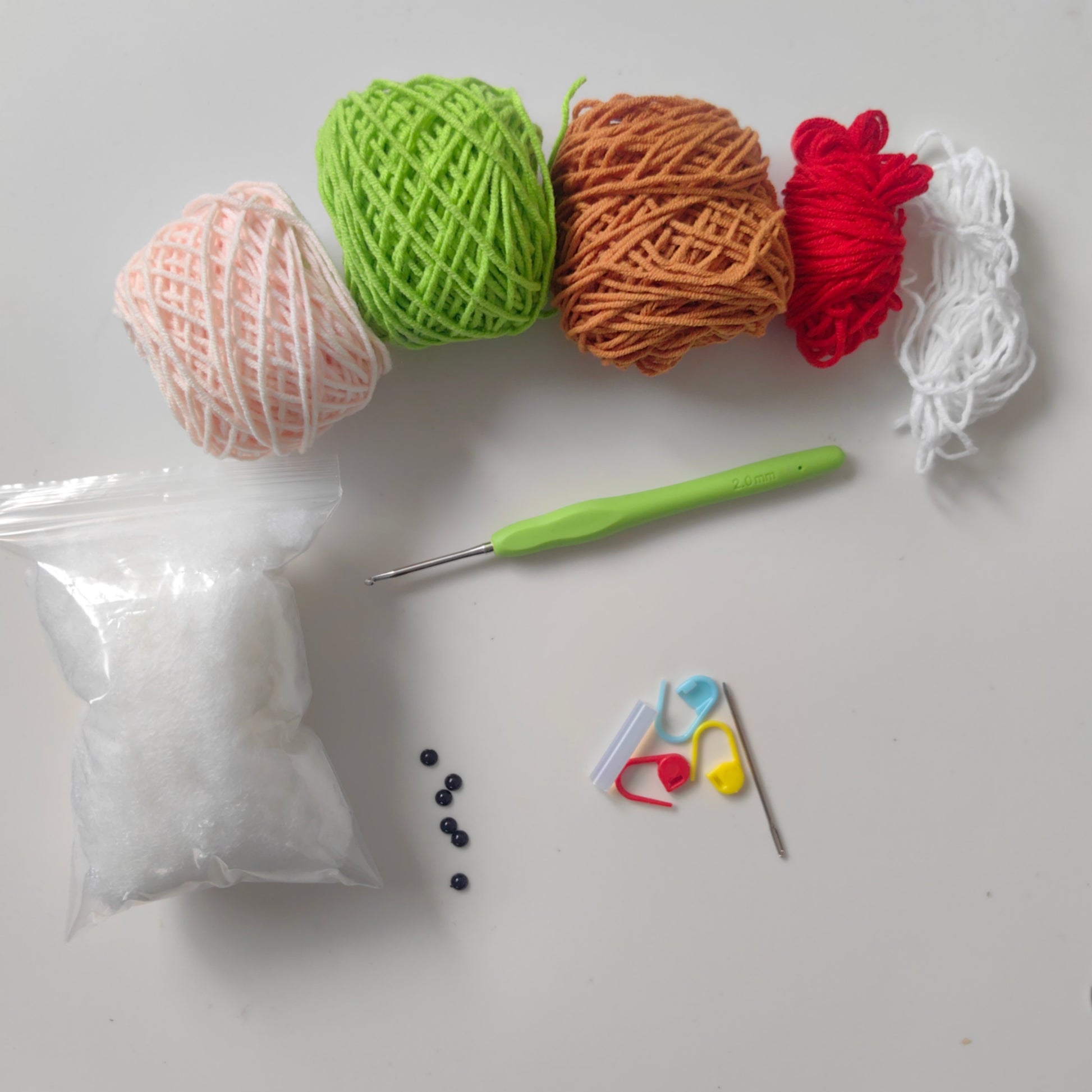 Complete crochet animal kit materials including yarn, crochet hook, stuffing, accessories, and instructions