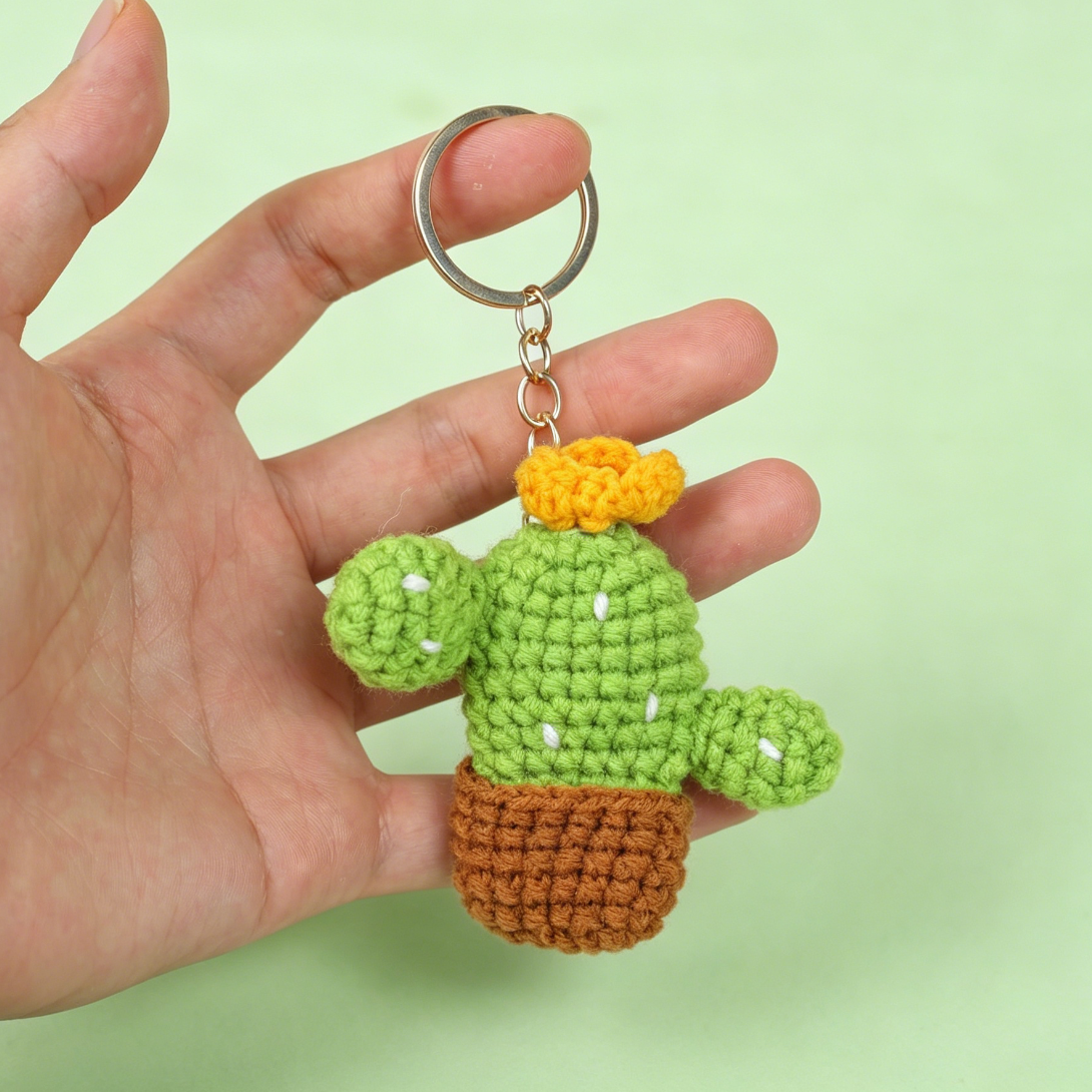 crochet cactus keychains hanging on a finger with keychain accessories included