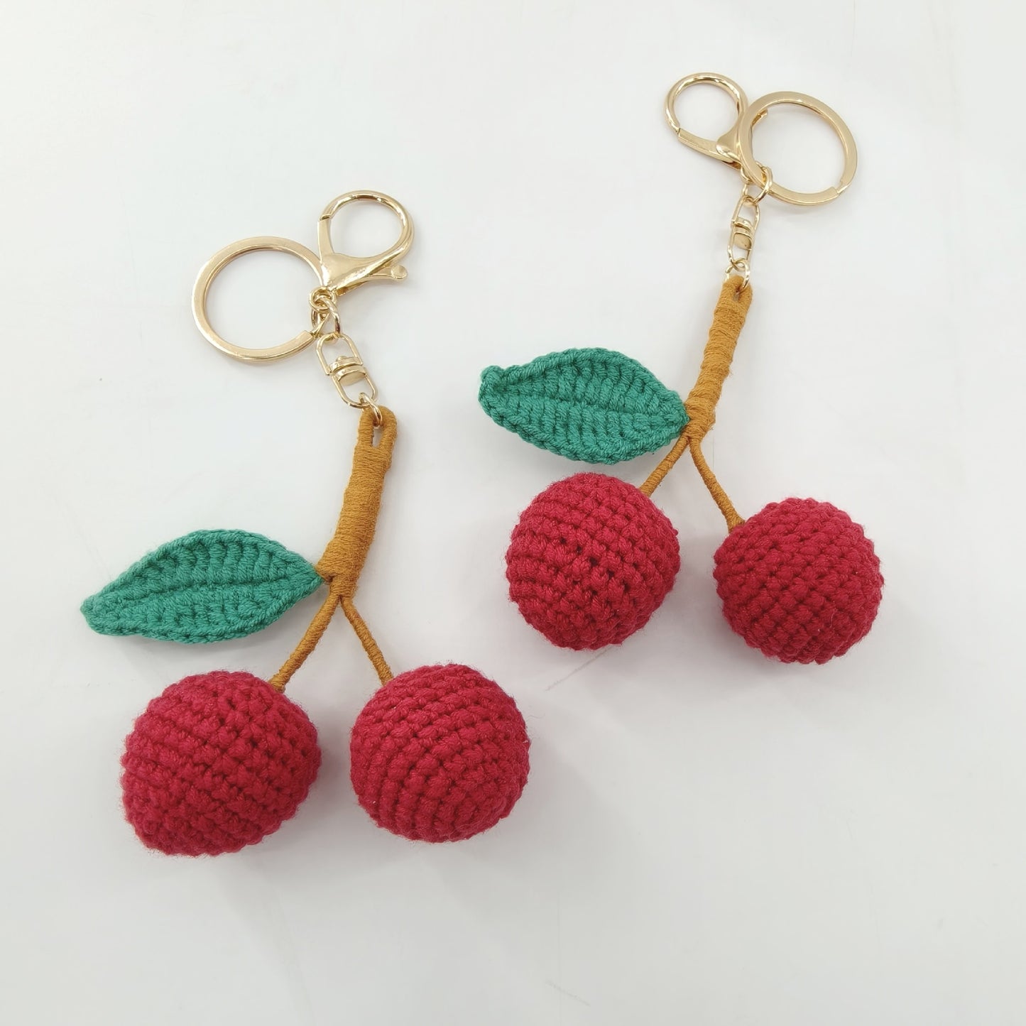 Close-up detail of crochet cherry keychain showing handmade stitching, leaf details, and soft yarn texture