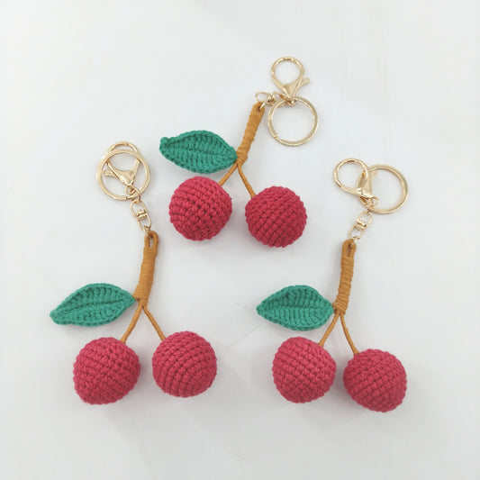 Three cute crochet cherry keychains displayed together, handmade cherry bag charms from Little Loop Crochet.