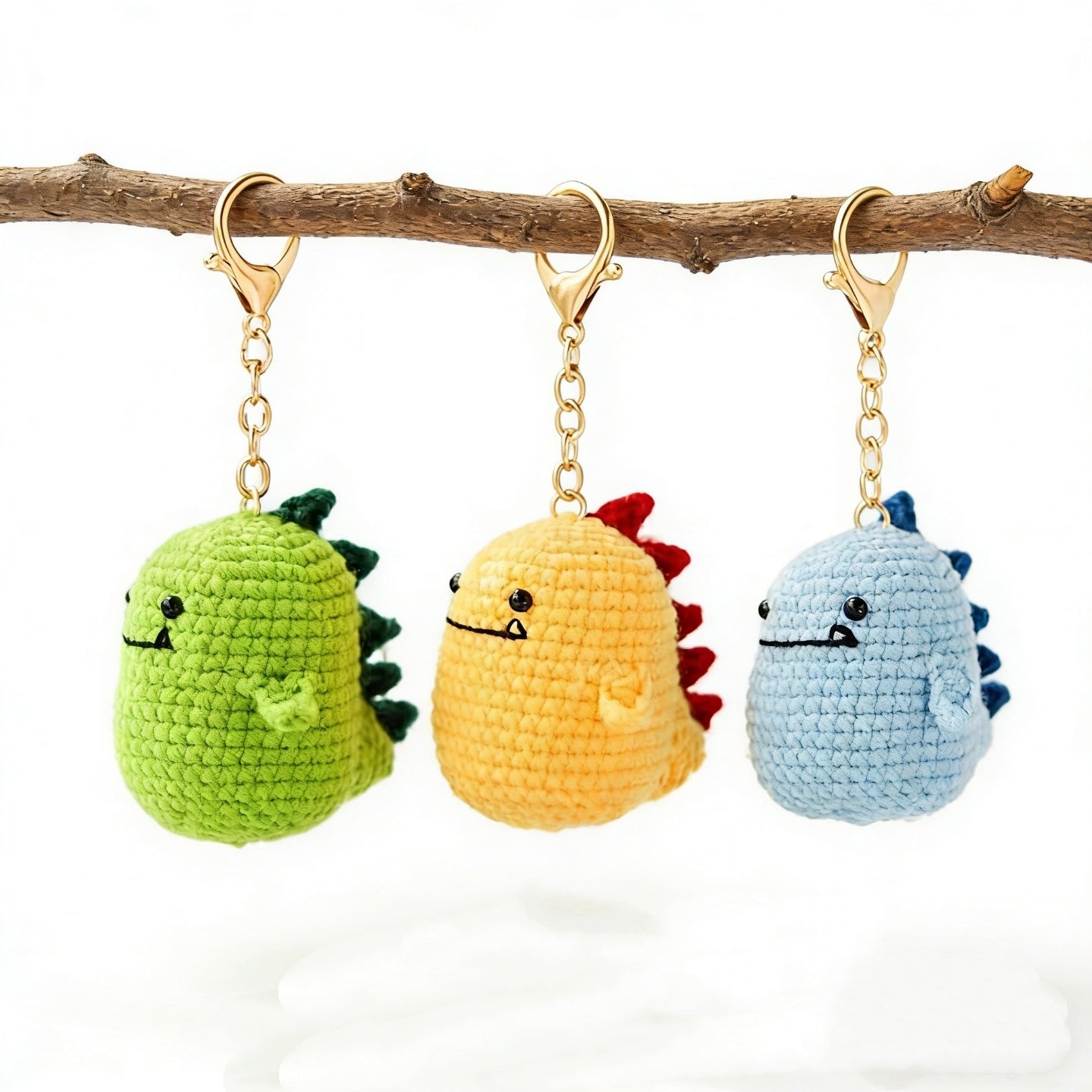 Crochet dinosaur keychain kit with green, yellow, and blue dinosaur designs displayed together