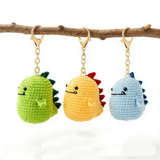 Crochet dinosaur keychain kit with green, yellow, and blue dinosaur designs displayed together