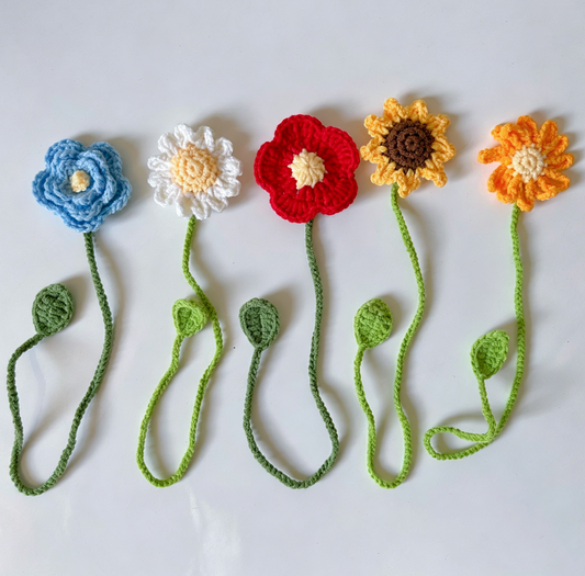 Five crochet flower bookmarks including sunflower, daisy, blue, red and orange flower designs displayed together
