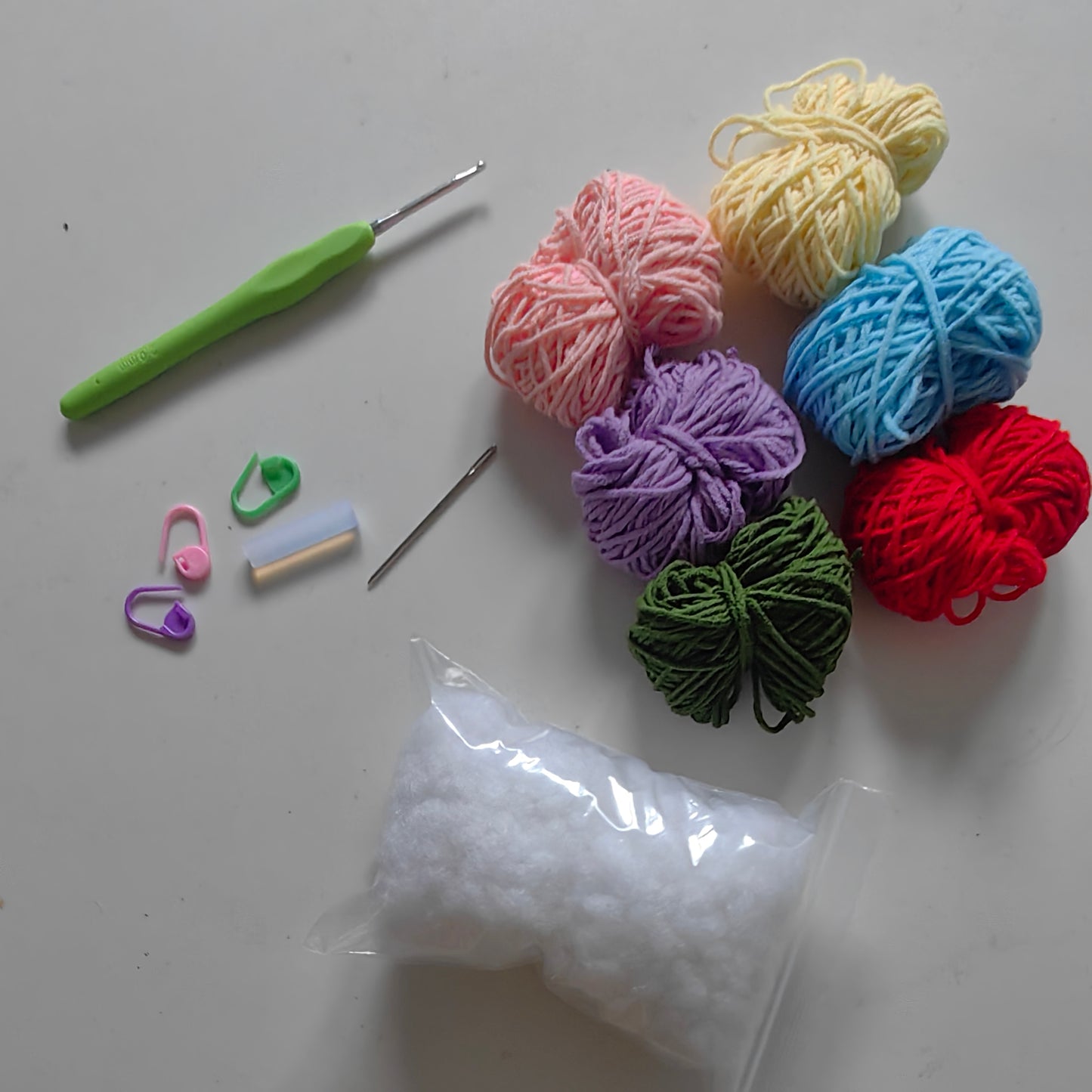 Complete crochet flower keychain kit materials including yarn, crochet hook, keychain hardware, stuffing, and accessories.