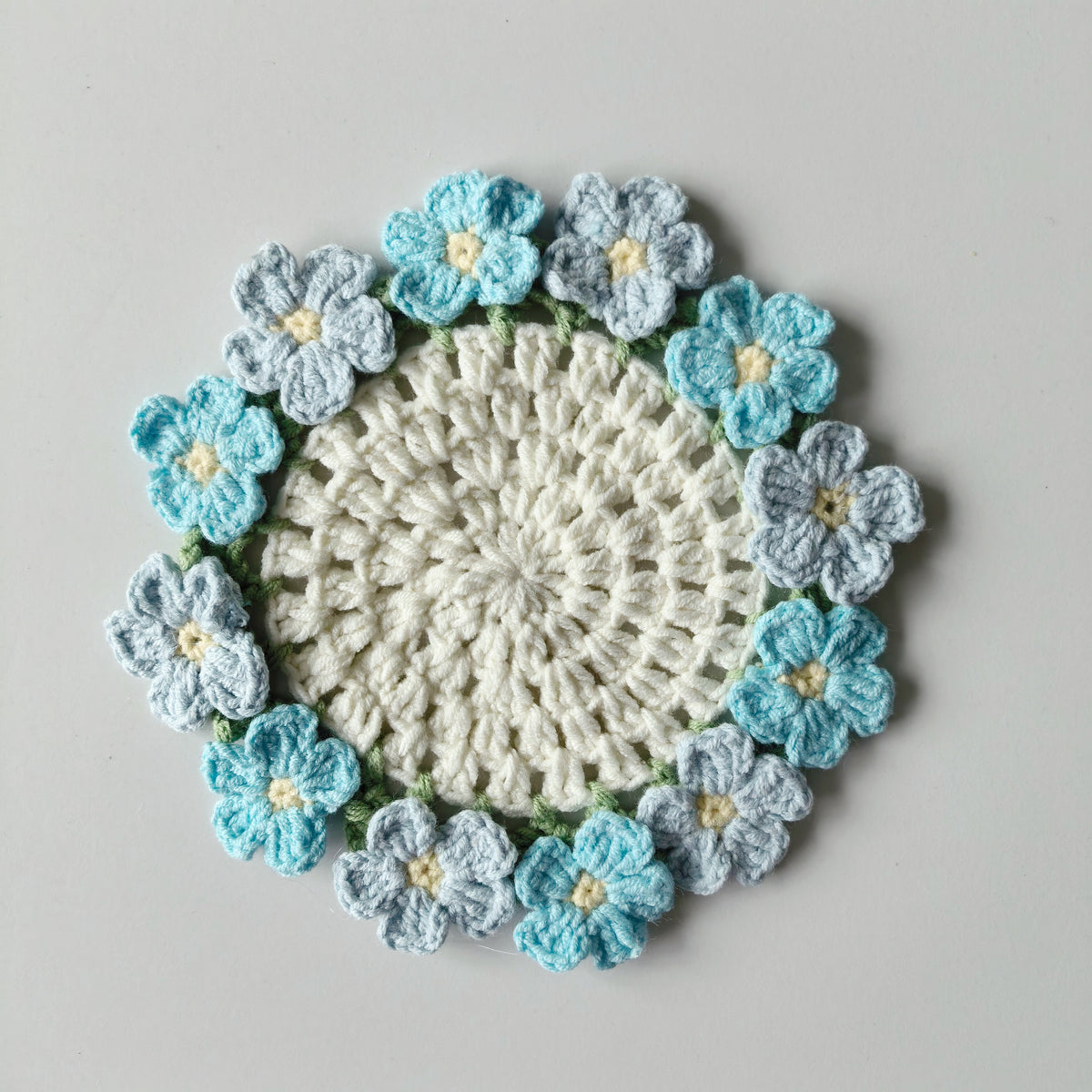 Crochet forget-me-not coaster kit displayed on a white background