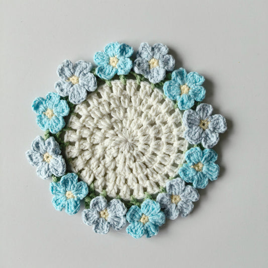 Crochet forget-me-not coaster kit displayed on a white background