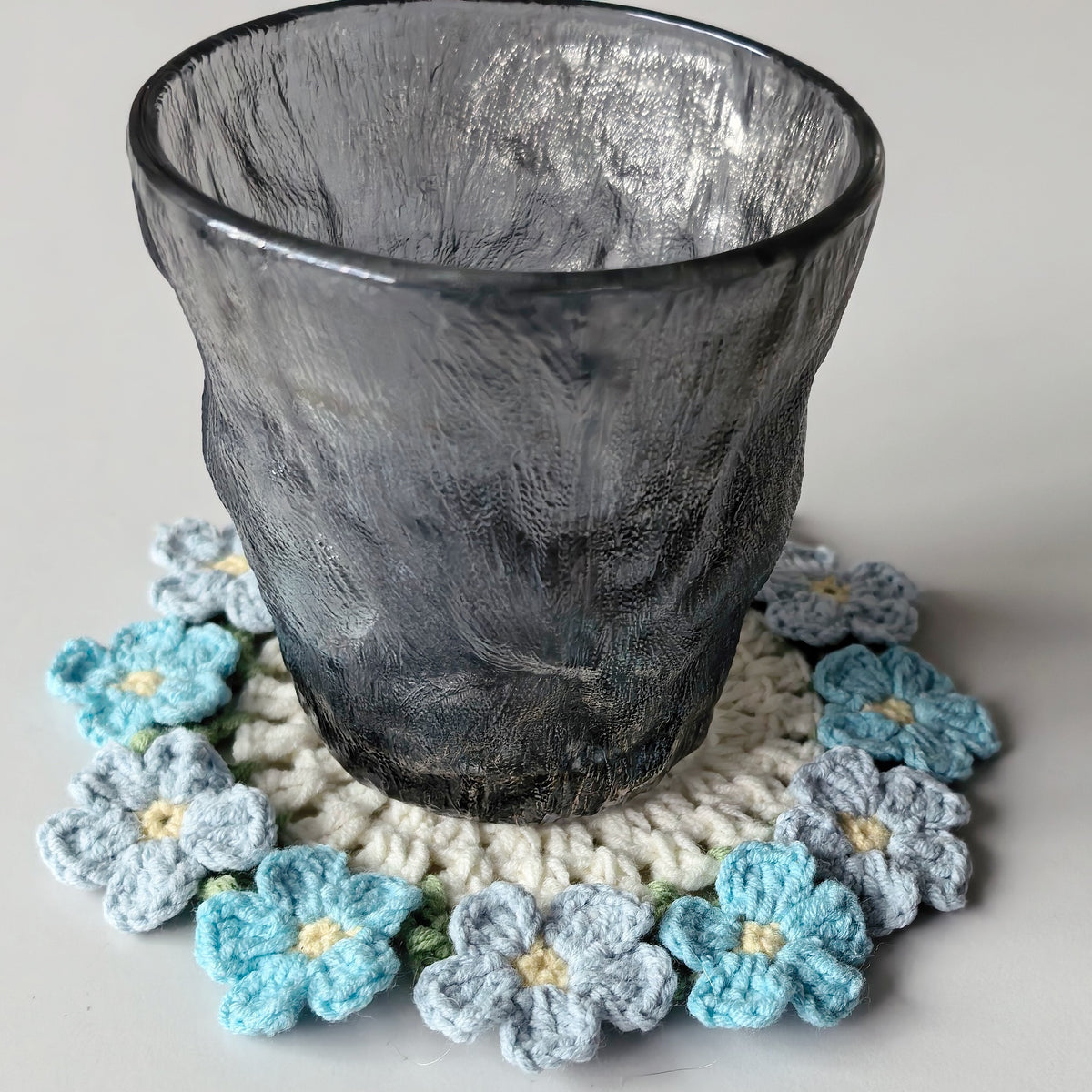 Crochet forget-me-not flower coaster with a cup