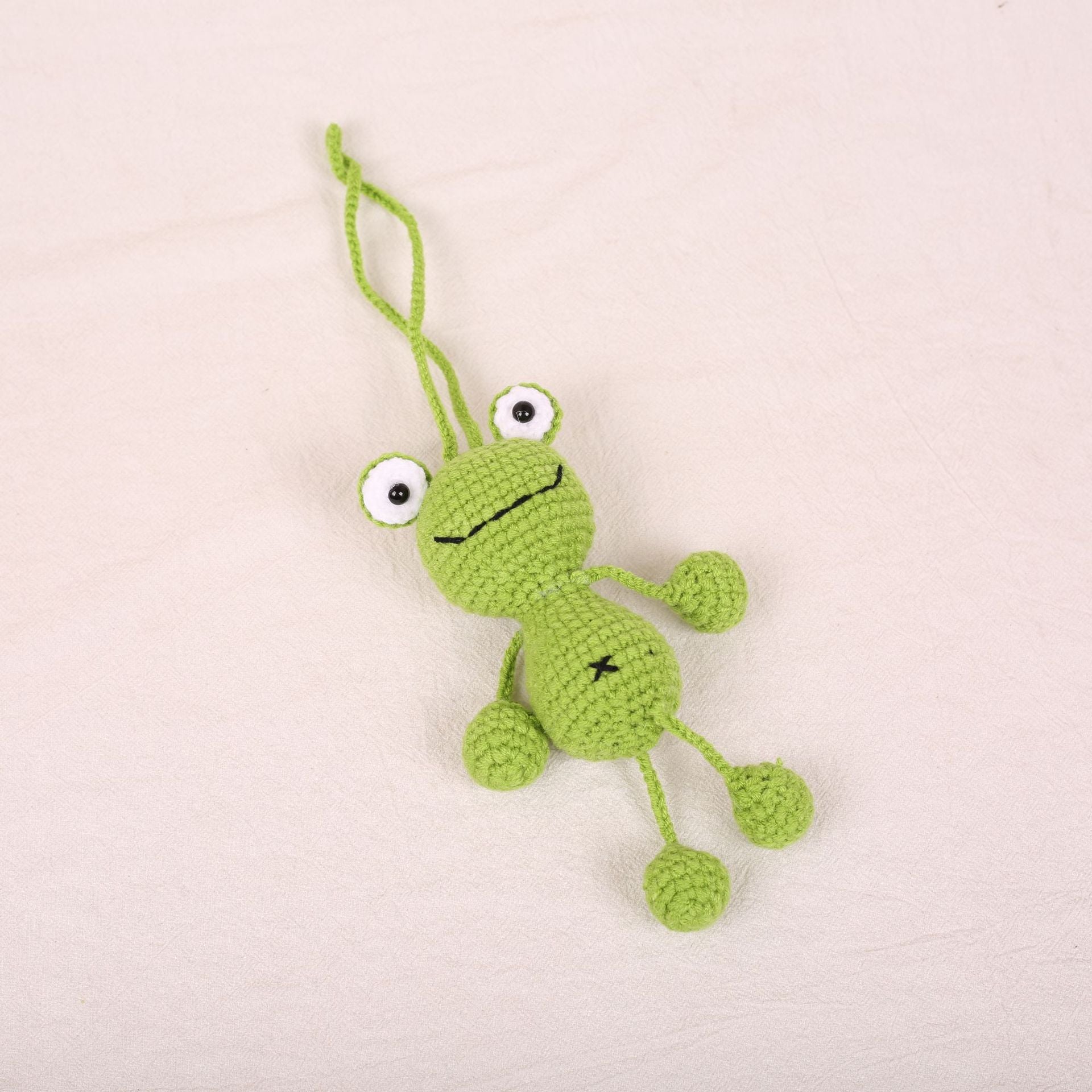 Handmade crochet frog plush keychain with hanging legs made from DIY crochet kit
