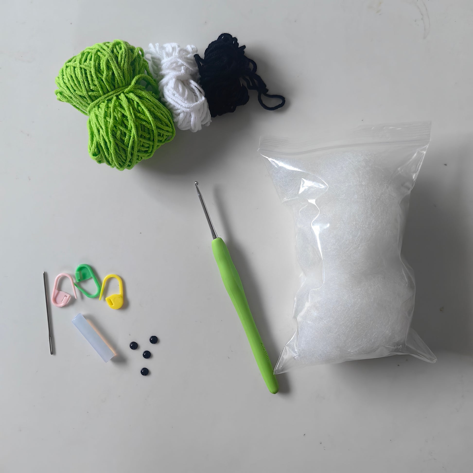 Crochet hanging frog kit materials including yarn, crochet hook, stuffing and accessories