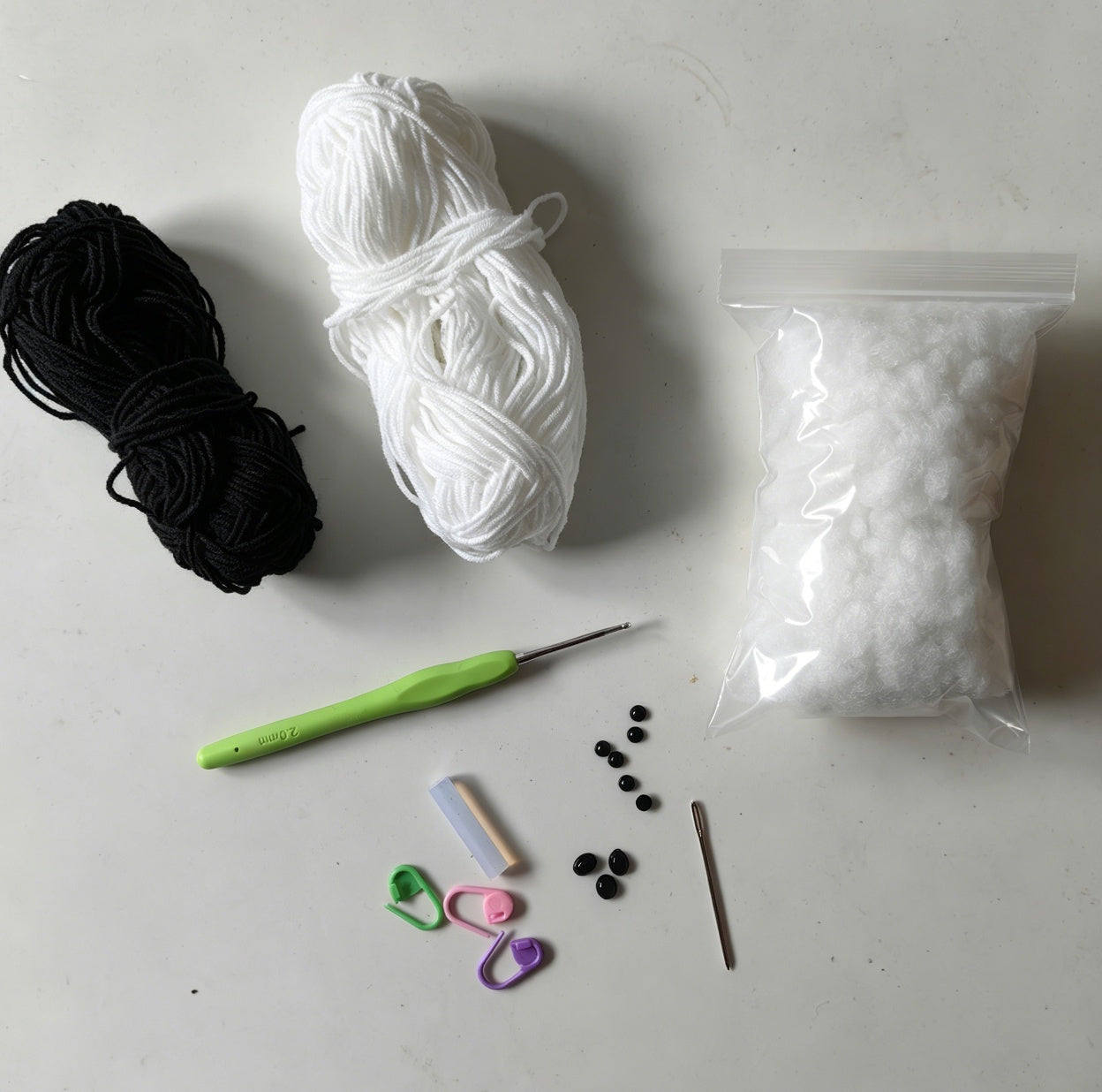 Complete crochet panda plush kit including yarn, stuffing, crochet tools, accessories, and materials needed to make three panda keychains