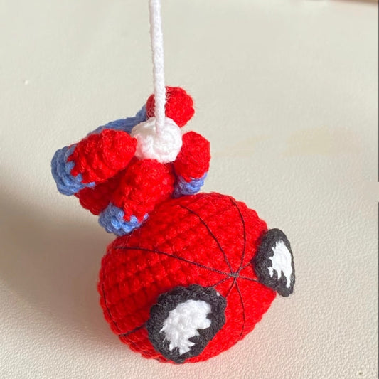 Cute crochet Spider-Man hanging upside down from a white spider web