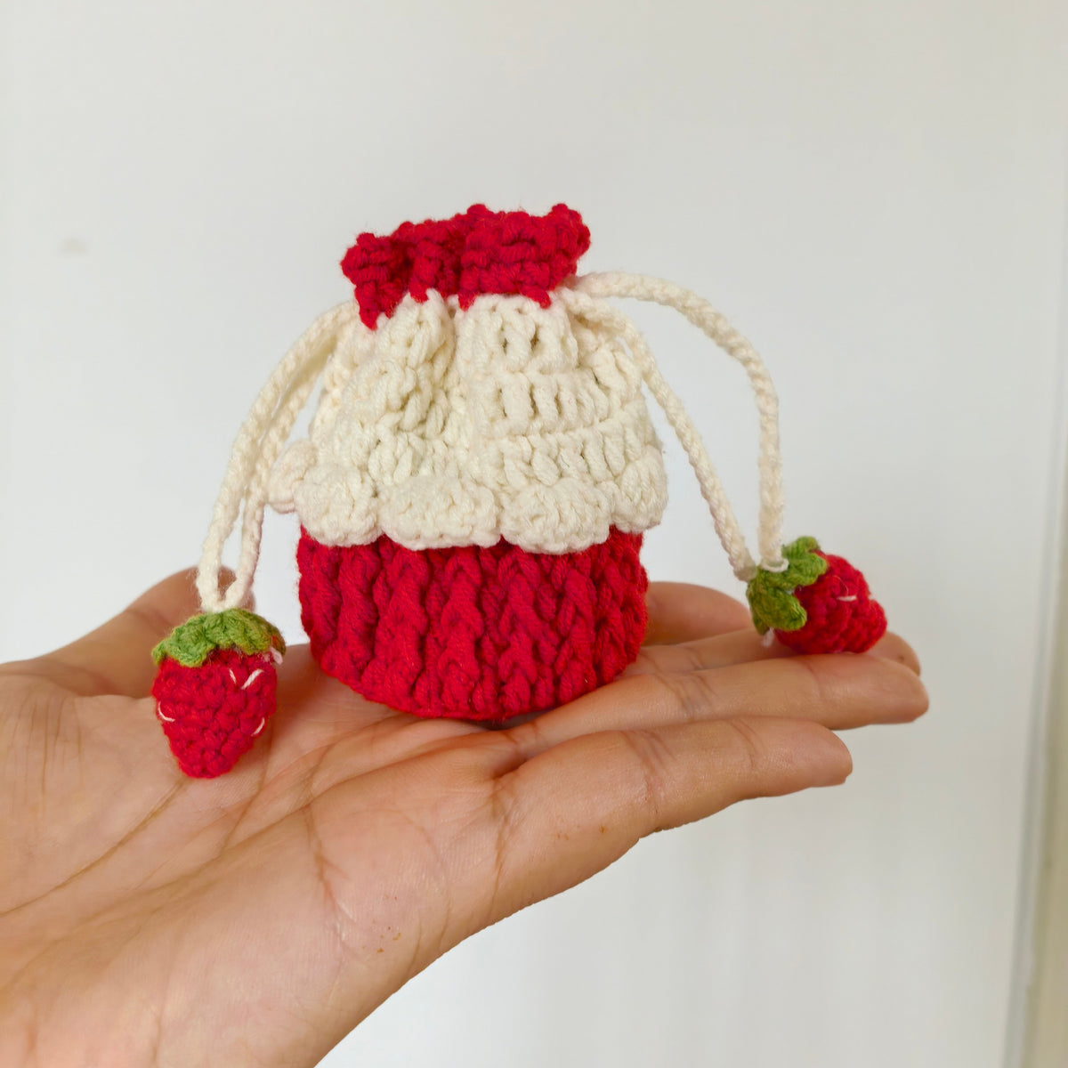 Mini crochet strawberry drawstring purse held in hand