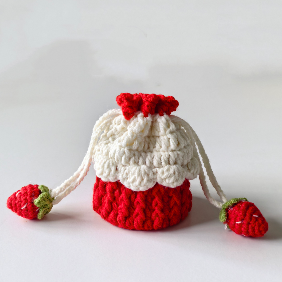 Mini crochet strawberry drawstring purse on a white background