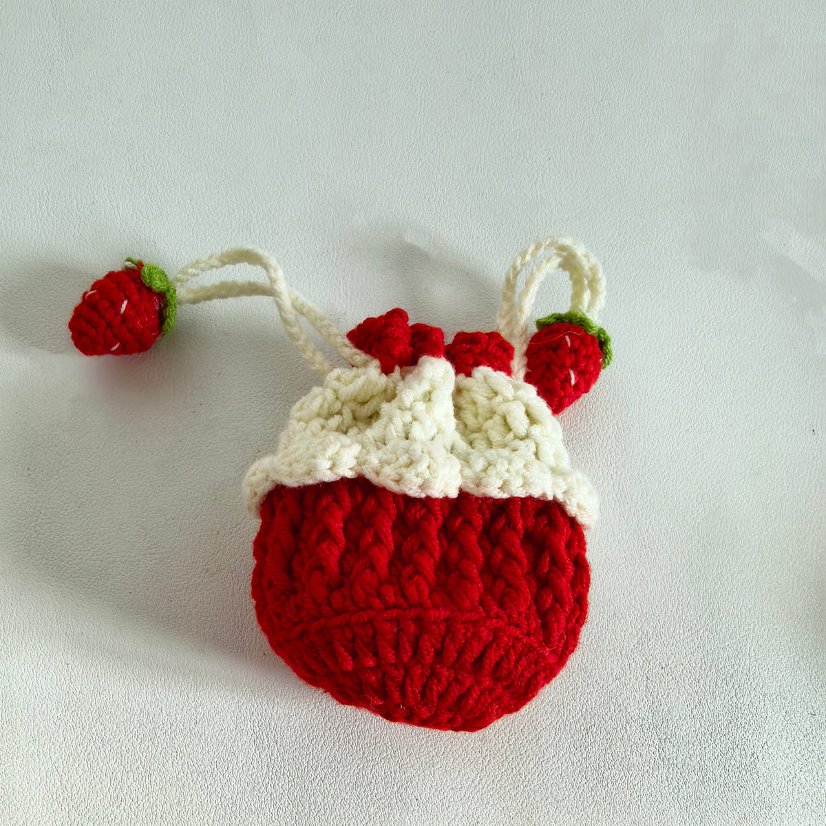 Side view of a mini crochet strawberry drawstring purse