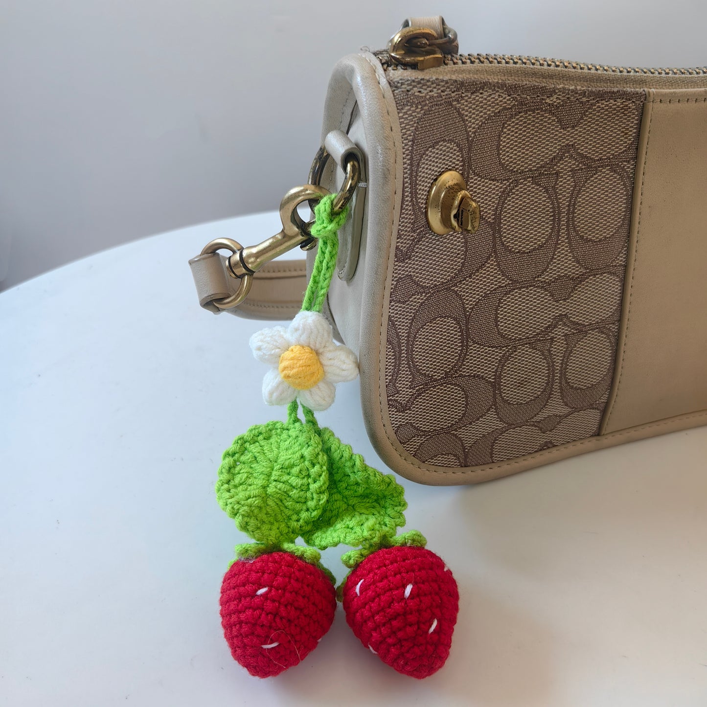 Crochet strawberry keychain attached to a handbag as a cute bag charm