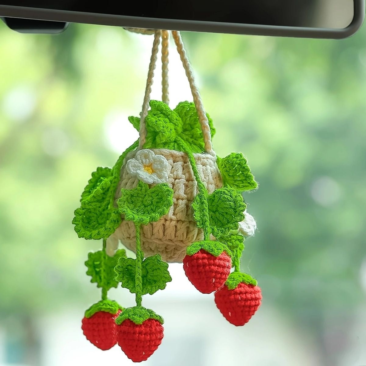 Finished crochet strawberry with mini basket hanging from a car rearview mirror