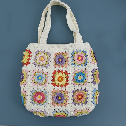 Floral granny square crochet tote bag laid flat, white base with colorful flower patterns