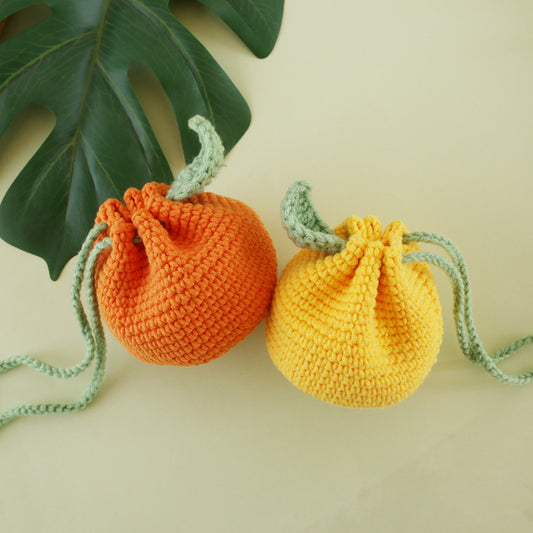 Handmade crochet drawstring bag, orange and yellow, front view with green leaf