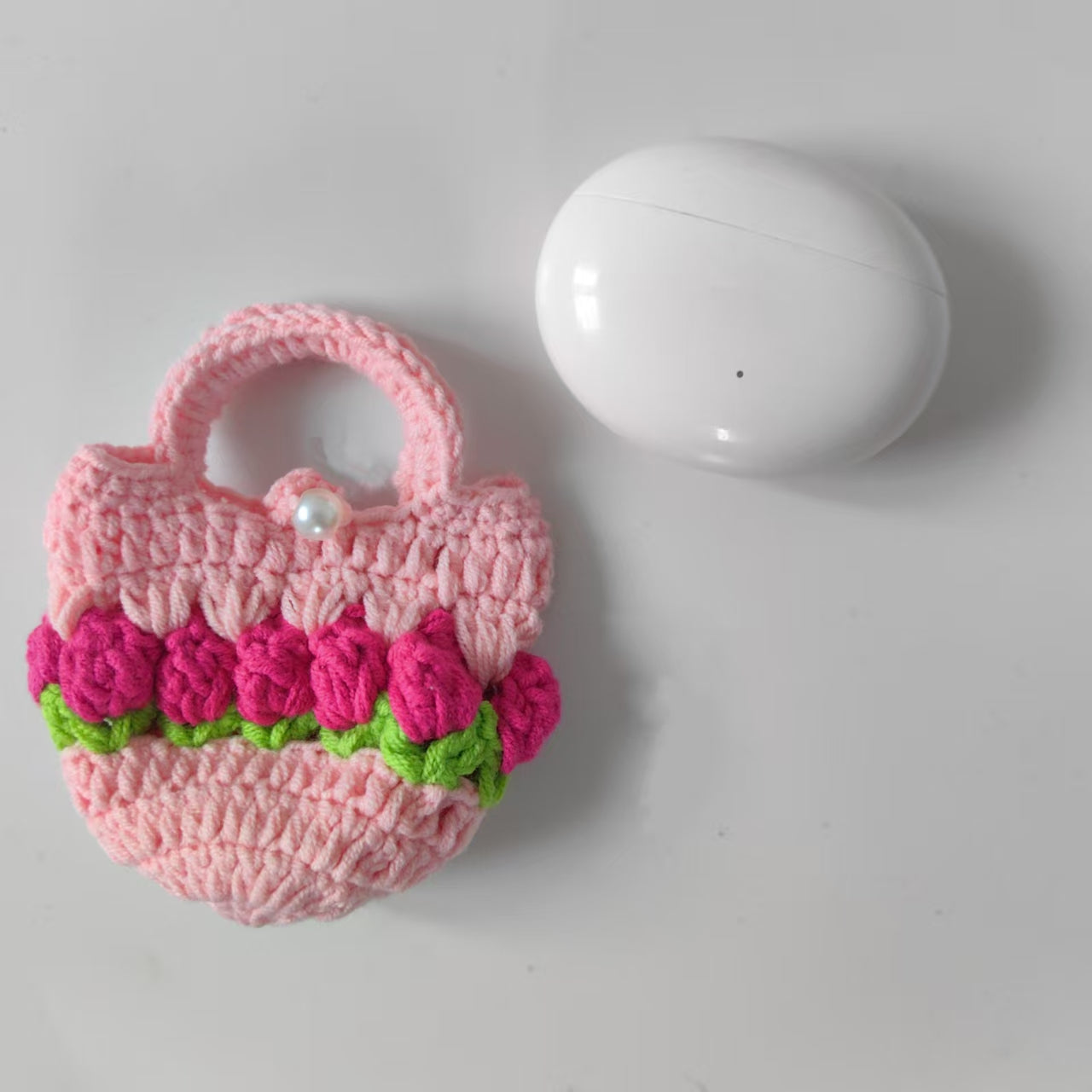 Pink crochet mini tulip pouch holding AirPods earphones
